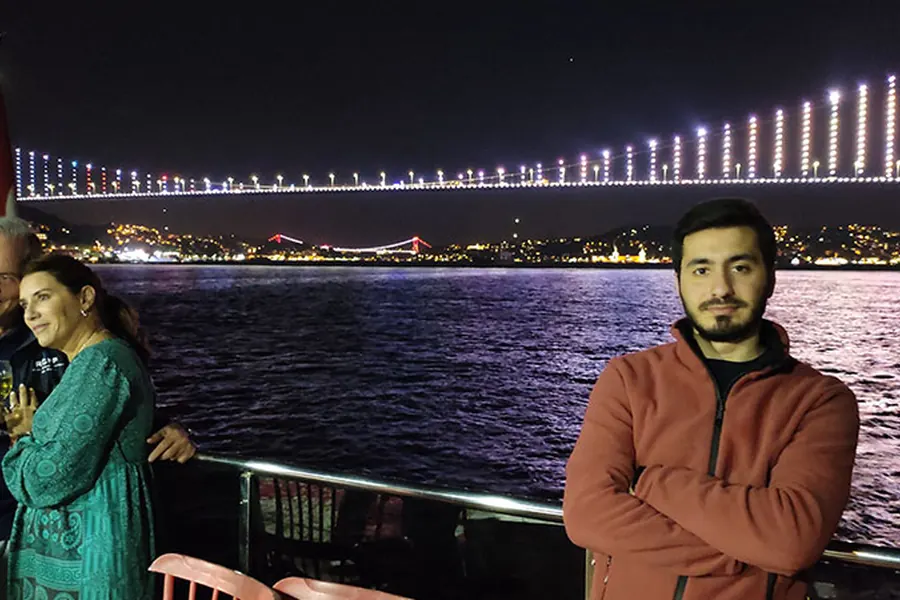 Guests on deck in front of the illuminated Bosphorus Bridge at night