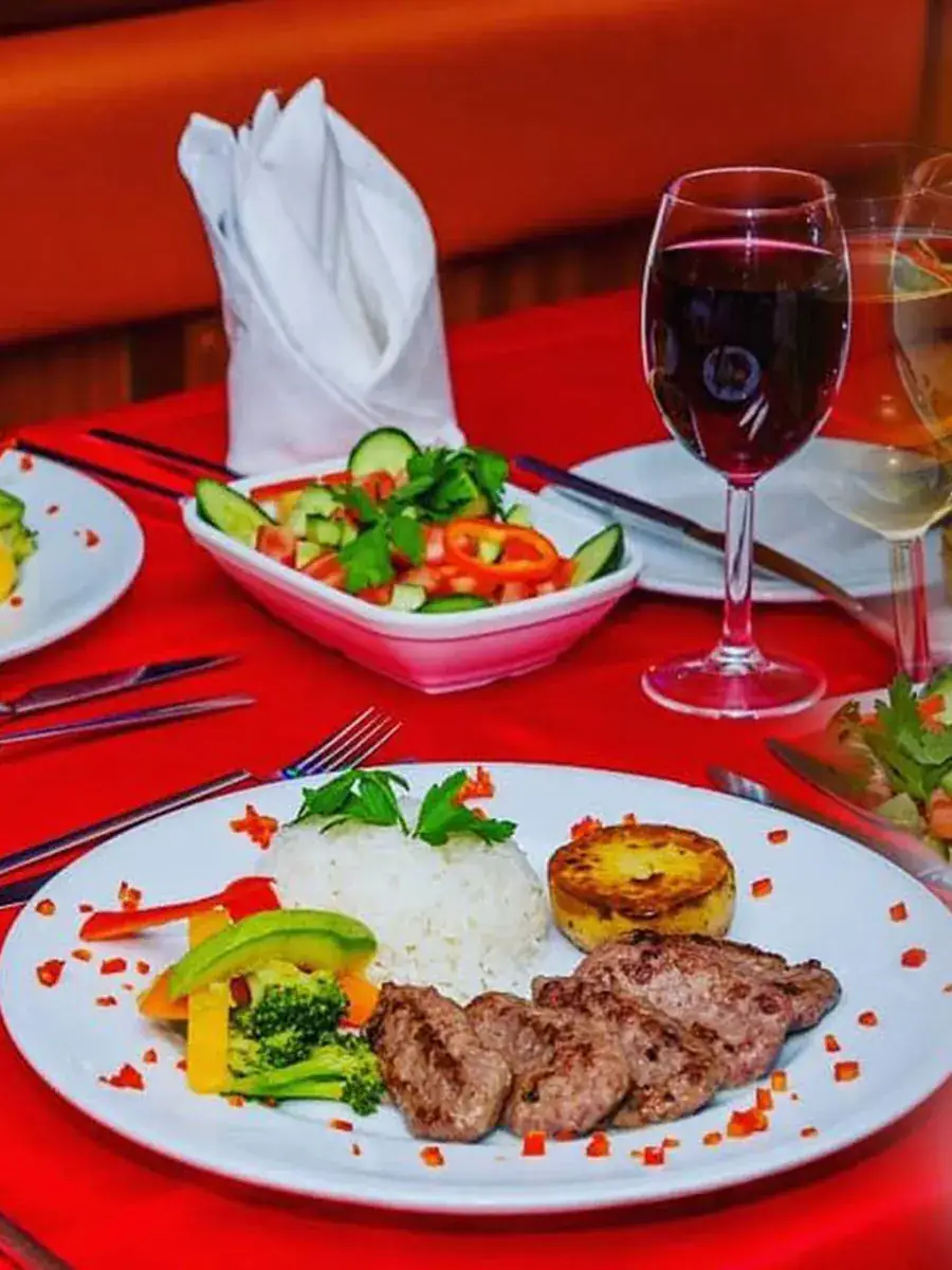 Grilled meat main course with salad and red wine on the dinner cruise