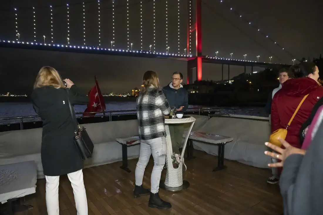 Guests on deck with the Bosphorus Bridge lit up at night