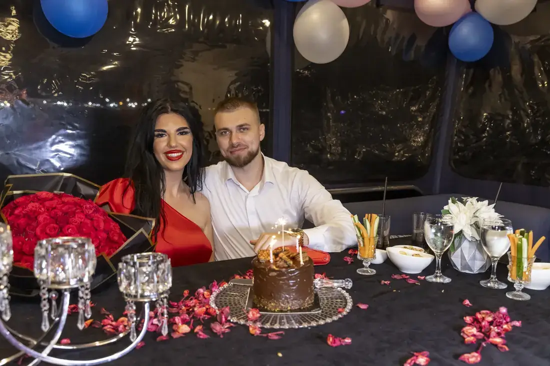 Couple with red roses and a cake after a proposal on a yacht