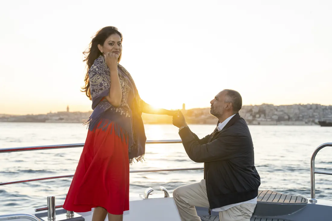 Man kneeling to propose on a yacht at sunset