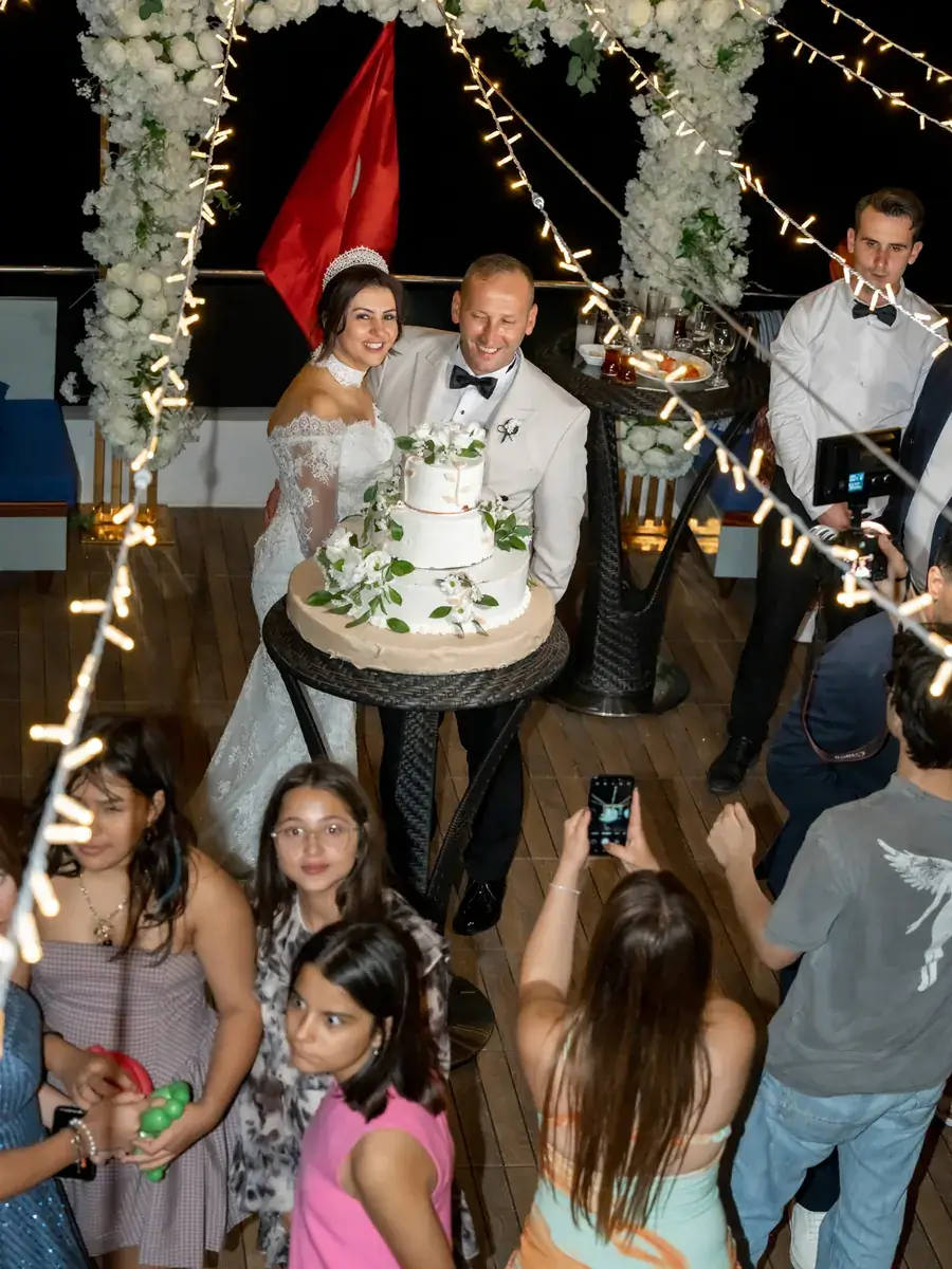 Newlyweds with the wedding cake among the guests