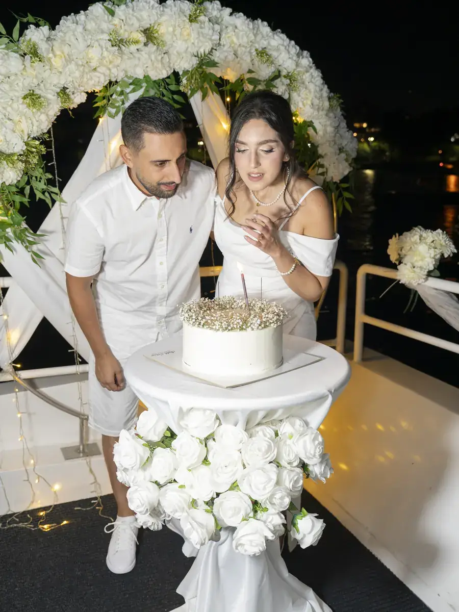Pareja cortando la tarta nupcial bajo un arco de flores