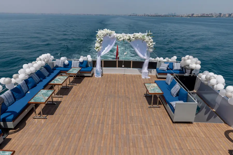 Yacht deck set for a wedding ceremony with a white flower arch