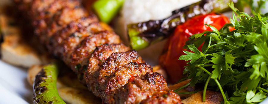 Kebab de Adana en brocheta con pimientos y tomates asados