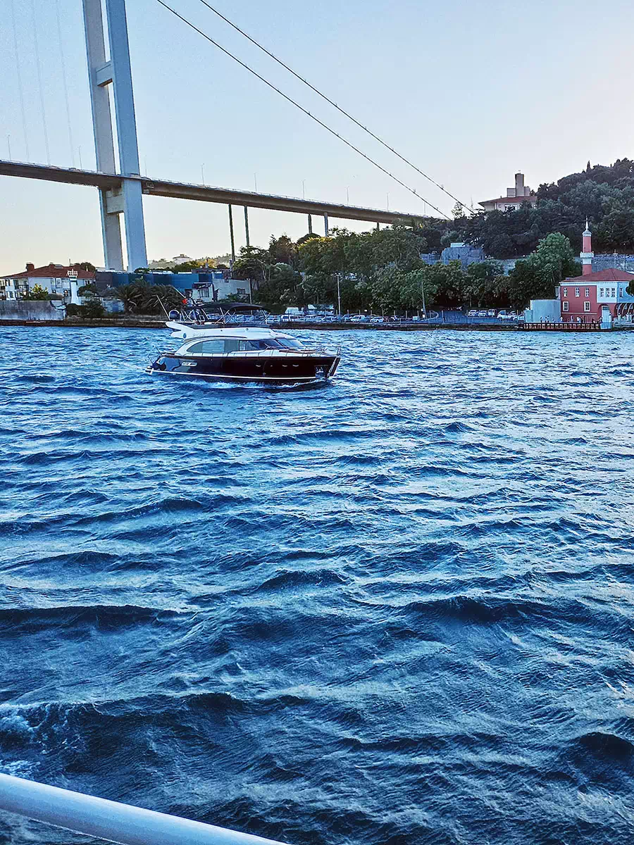 Private yacht passing a palace on the Bosphorus shore
